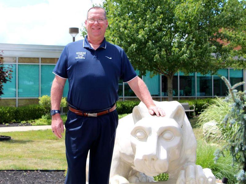 365英国上市新任高尔夫球总教练杜波依斯·约翰·施耐德站在校园内的狮子神龛前.